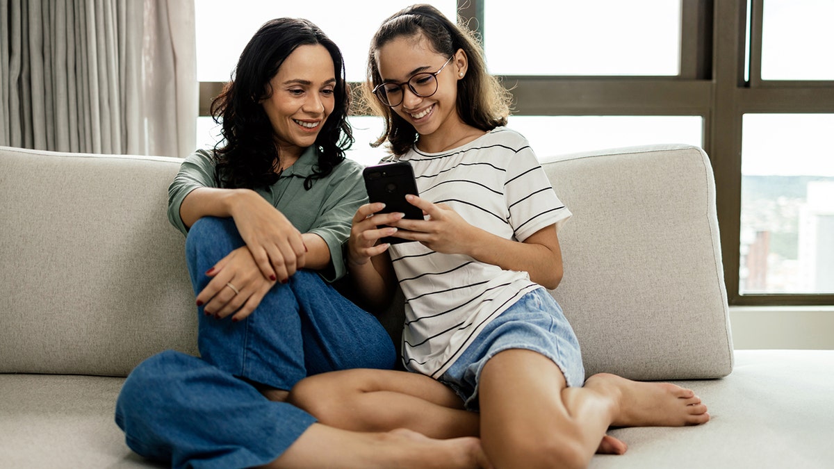 Mother and daughter on cellphone at home