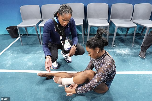 Biles has her ankle taped after competing on the uneven bars during the qualification round