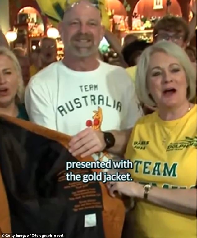 Ariarne Titmus's mother Robyn (left) hands over the gold jacket to Mollie O'Callaghan's parents Toni and Nick after her victory in the 200m freestyle in Paris