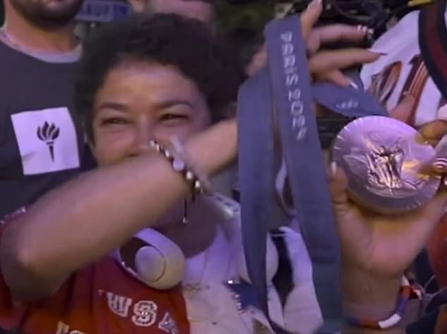 Nellie holds up her daughter's gold medal for the team all-around event at the Olympic games