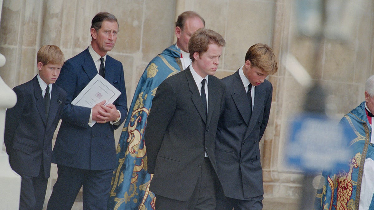 Prince Charles walking with Prince Harry, Prince William and Charles Spencer with their heads down during Princess Diana's funeral.