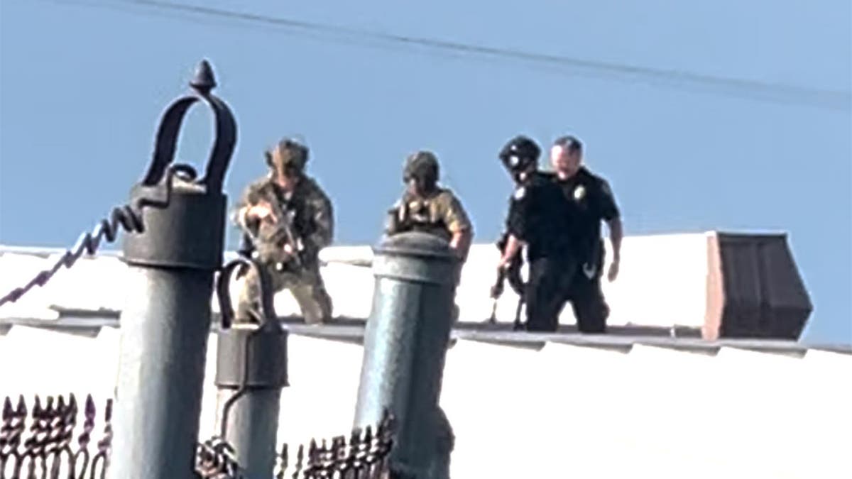 Law enforcement officers surround the body of Thomas Crooks, the would-be assassin, on the roof of a nearby building