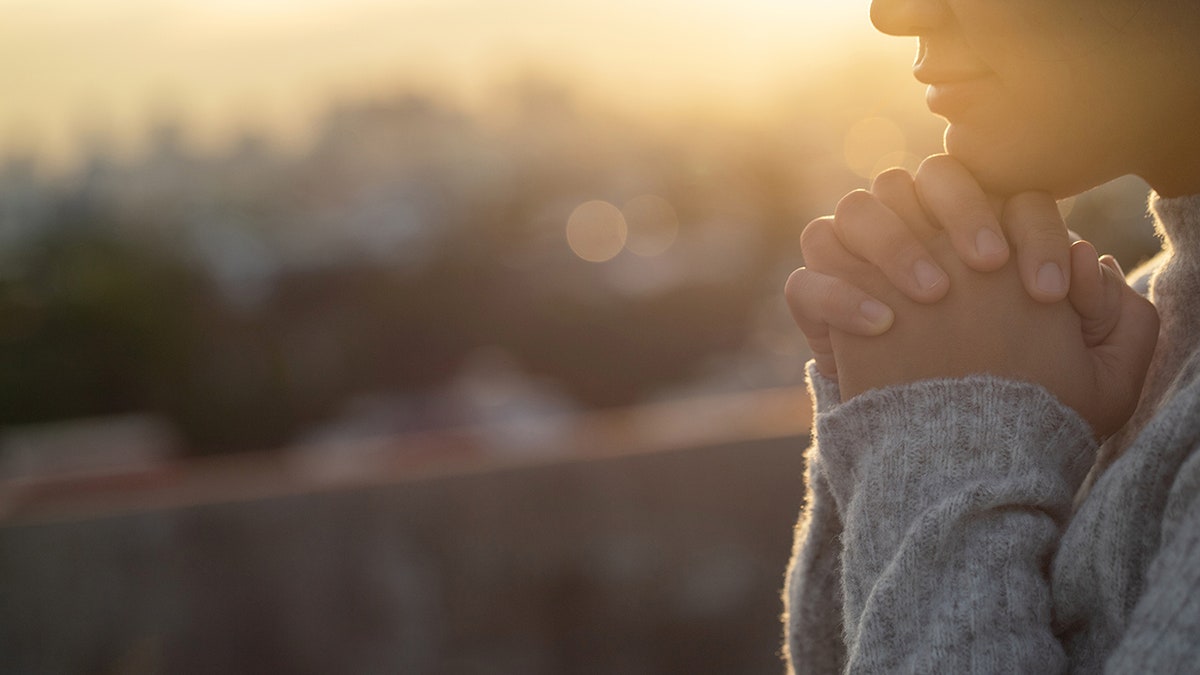 Woman praying during sunset.