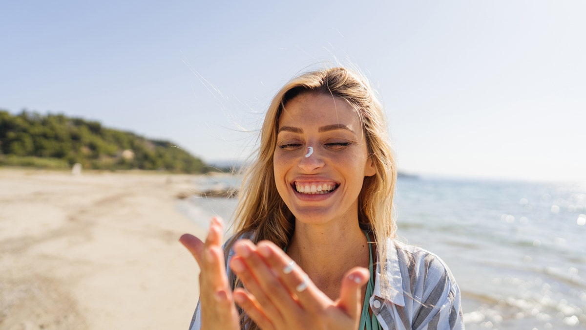 young woman applying sunscreen on her face