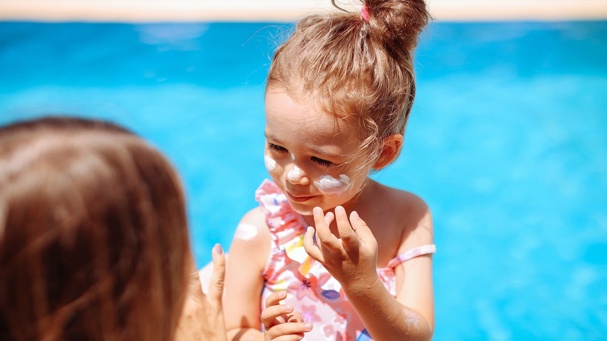 Child applying sunscreen