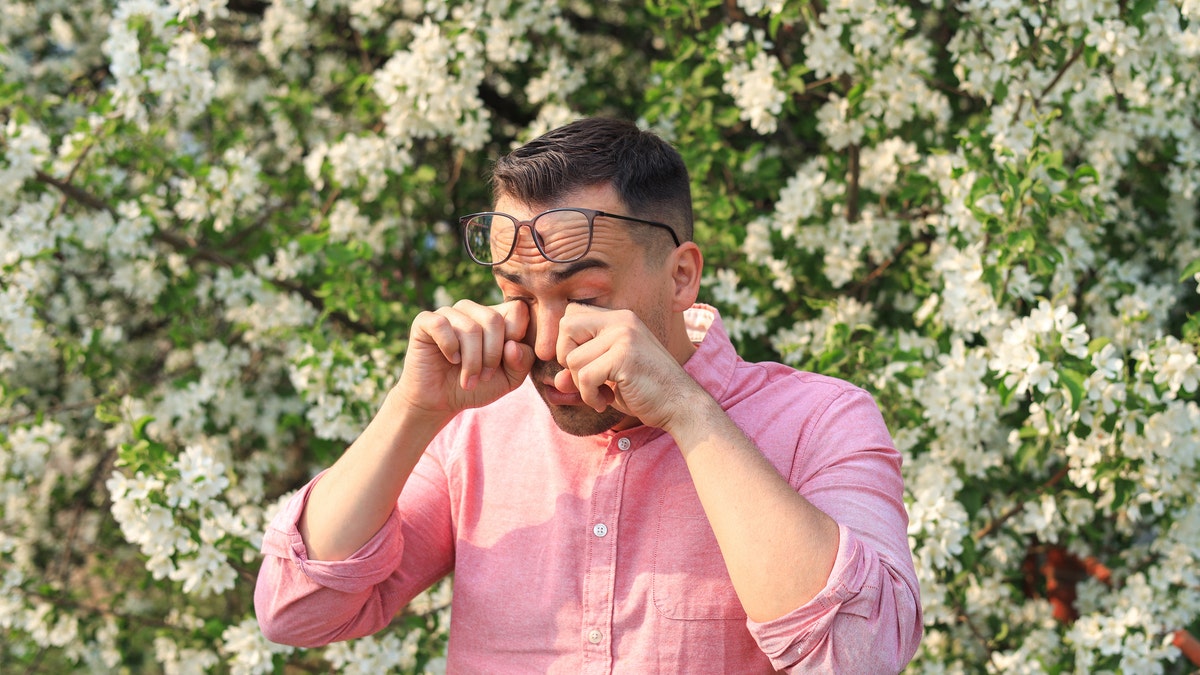 Man rubbing his eyes due to allergies