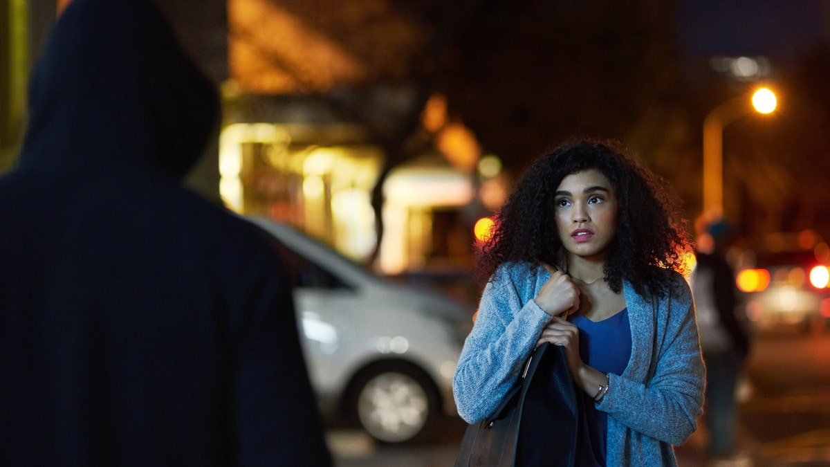 A woman facing a criminal at night