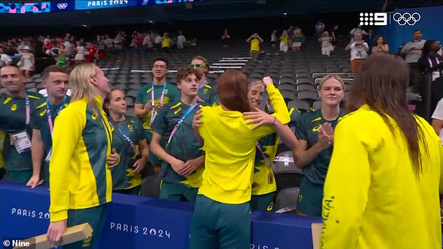 Australian swimming star Mollie O'Callaghan hanging her gold medal around Jamie Perkins' neck