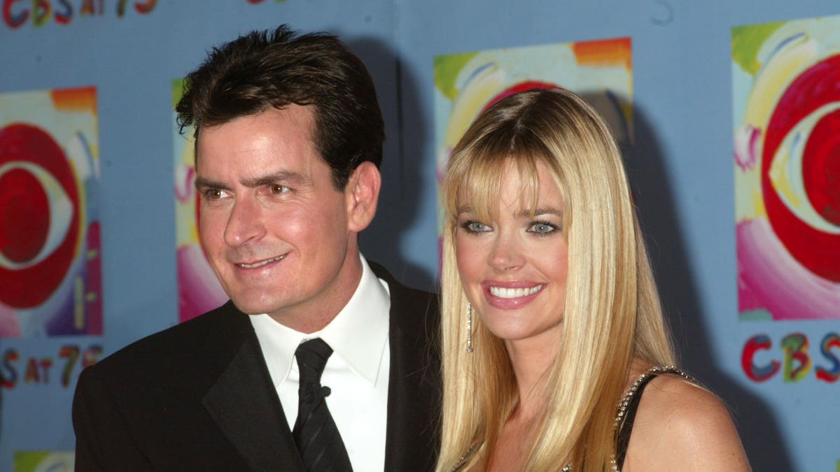 Charlie Sheen in a black suit and tie with Denise Richards in a black dress