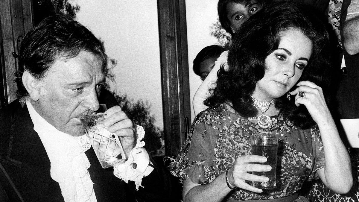 Elizabeth Taylor and Richard Burton share drinks at the table