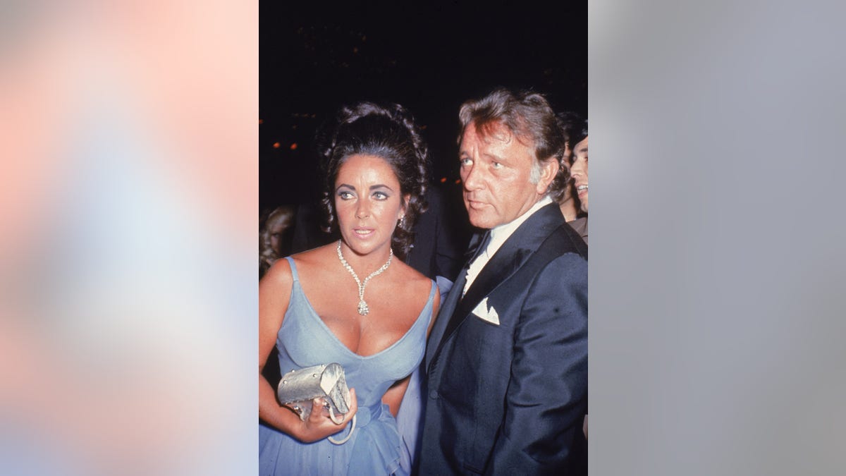 Elizabeth Taylor in a lavender gown next to Richard Burton in tuxedo.