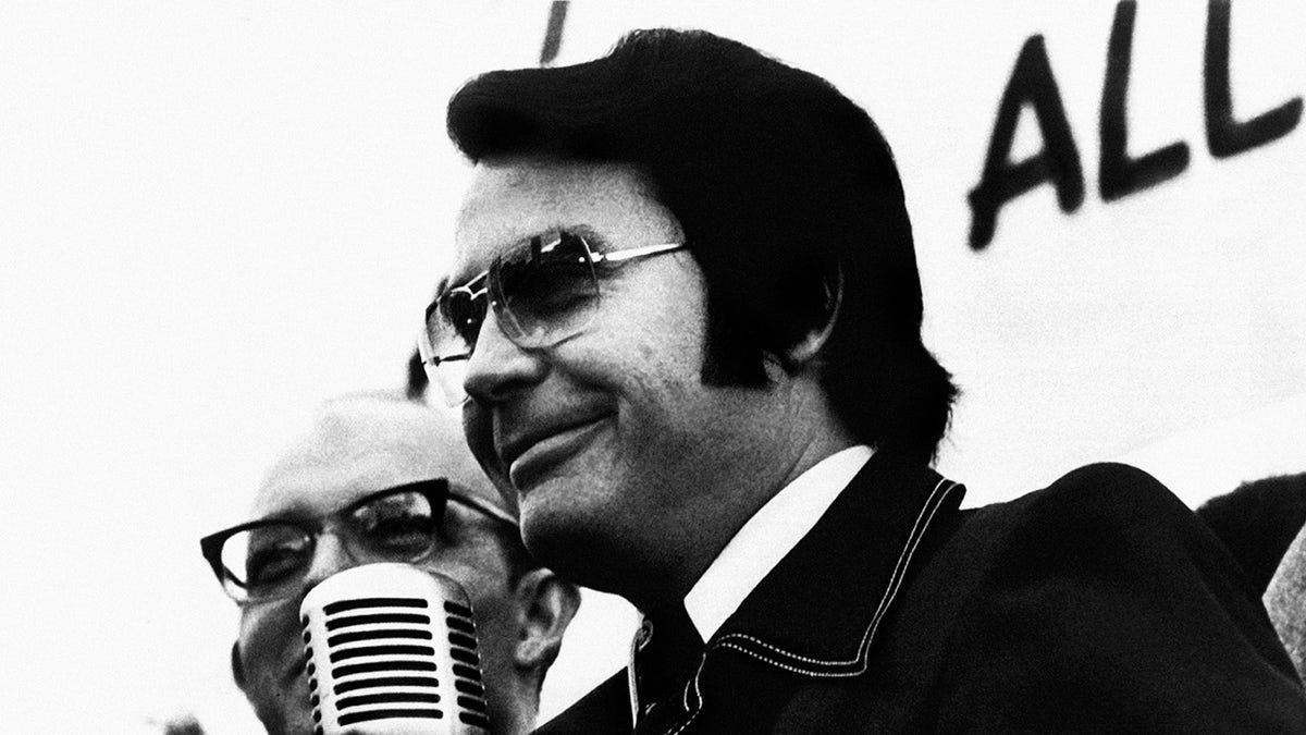 Jim Jones speaking into a microphone.