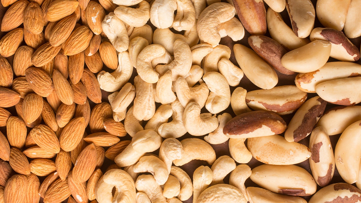 Almonds, cashews, and Brazil nuts arranged in a heart shape against a white backdrop.