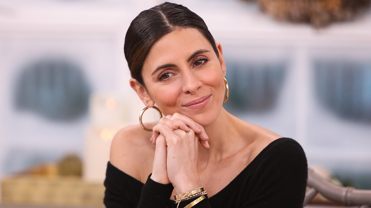 Jamie-Lynn Sigler in a black off-the-shoulder shirt, looking thoughtful