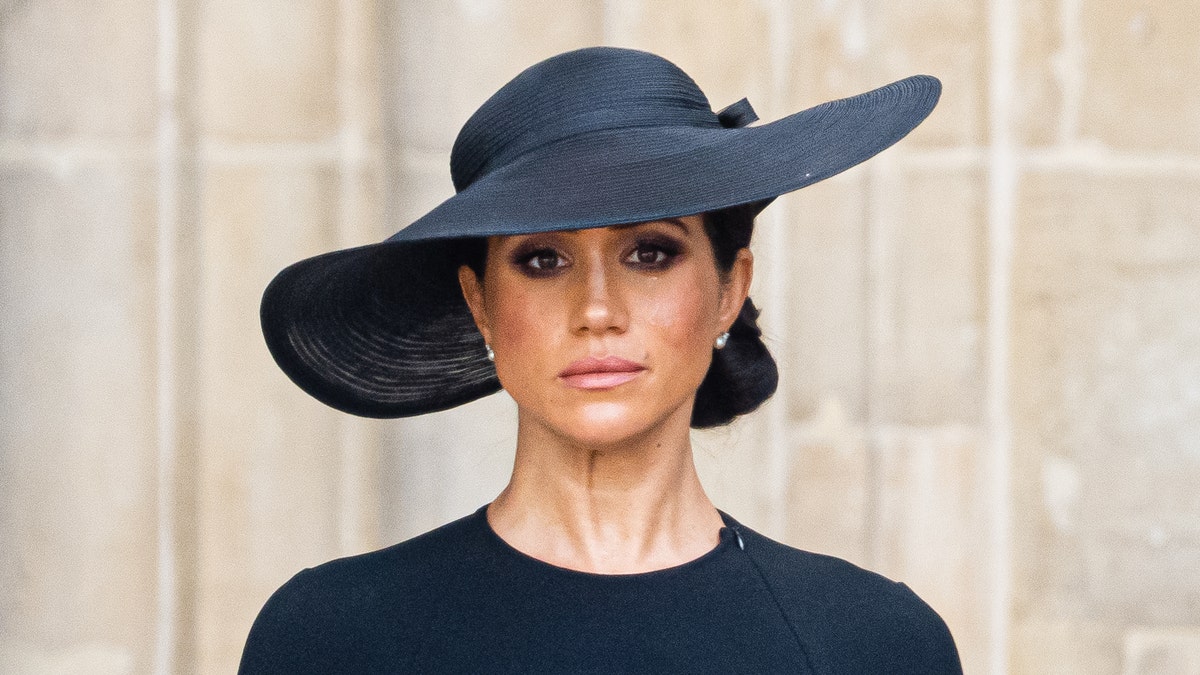 Meghan Markle attends Queen Elizabeth's funeral in a black dress and hat.